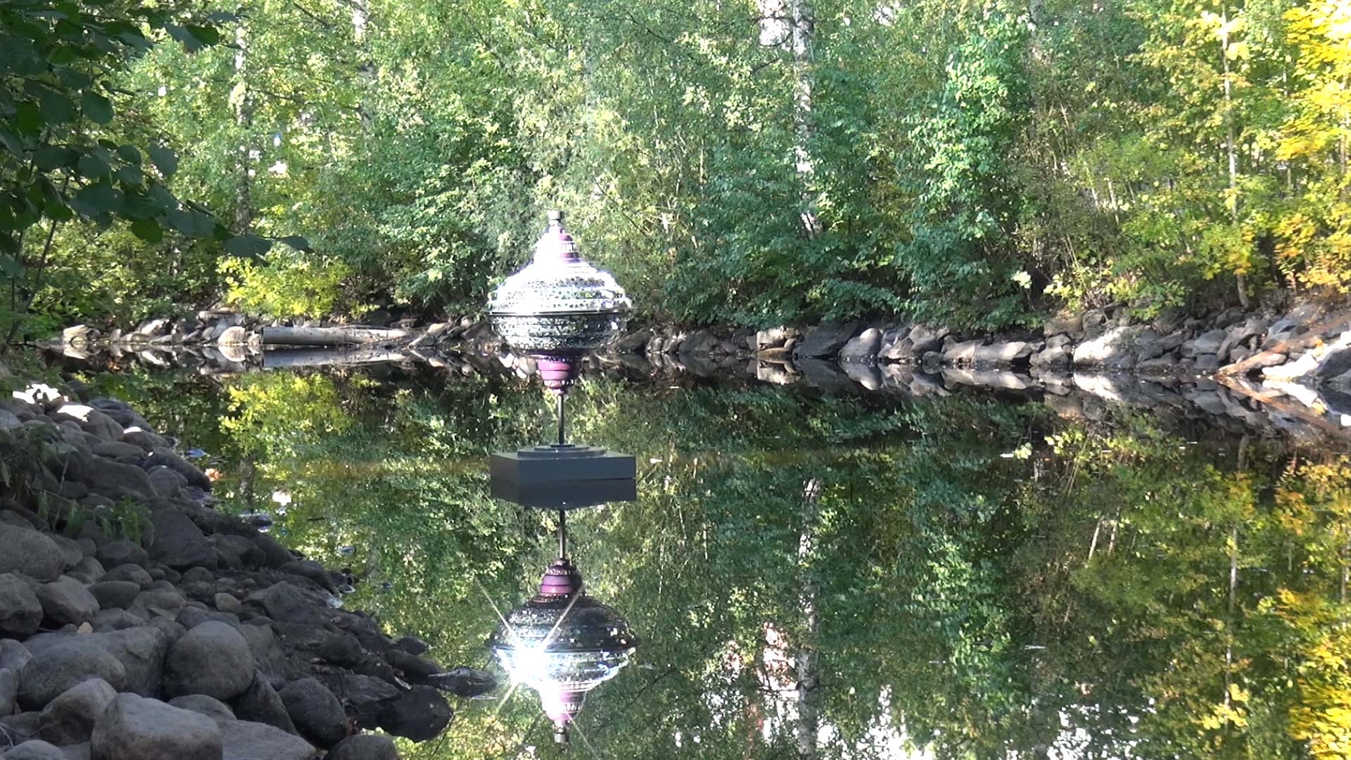 Fragmented Appearances — sculpture under a graffiti bridge tunnel by the water, projecting pink light at night